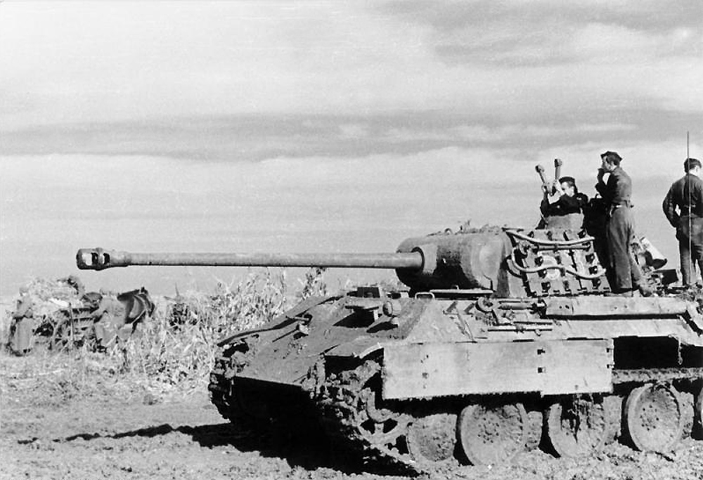 A left-side view of a mud-covered German Panther tank of 23. Panzer-Division somewhere in eastern Hungary, 1944. The commander uses a scissor periscope. Two other men stand behind him.